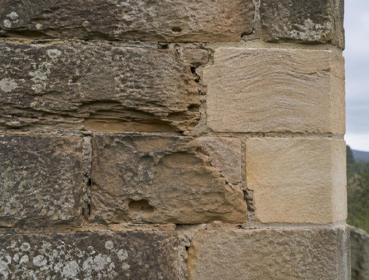 Eroded sandstone wall partly repaired with newly cut matching stone